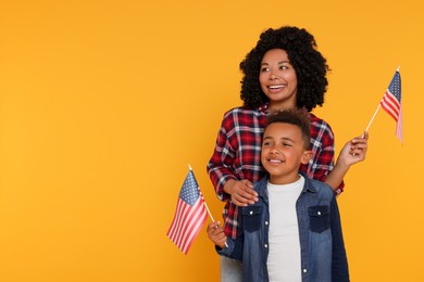 4th of July - Independence Day of USA. Happy woman and her son with American flags on yellow background, space for text
