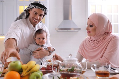 Happy Muslim family with little son at served table in kitchen