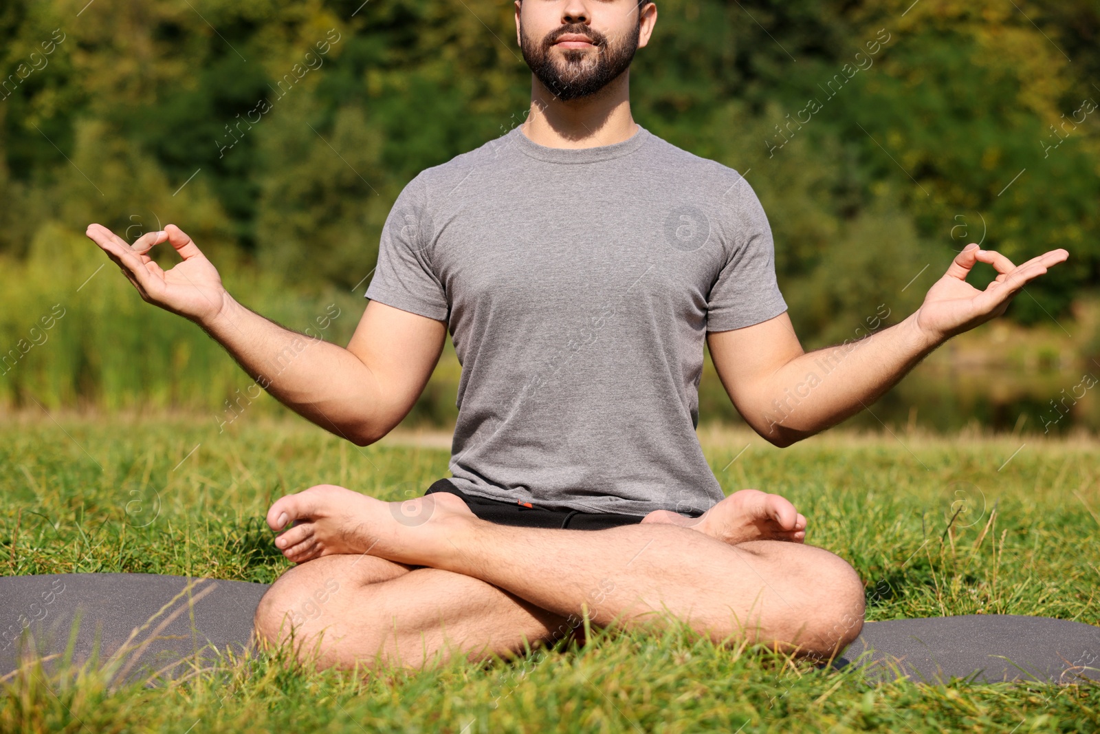 Photo of Man practicing yoga on mat outdoors, closeup. Lotus pose