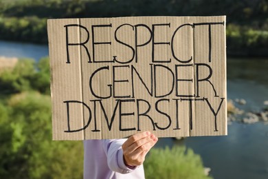 Photo of Woman holding sign with text Respect Gender Diversity outdoors
