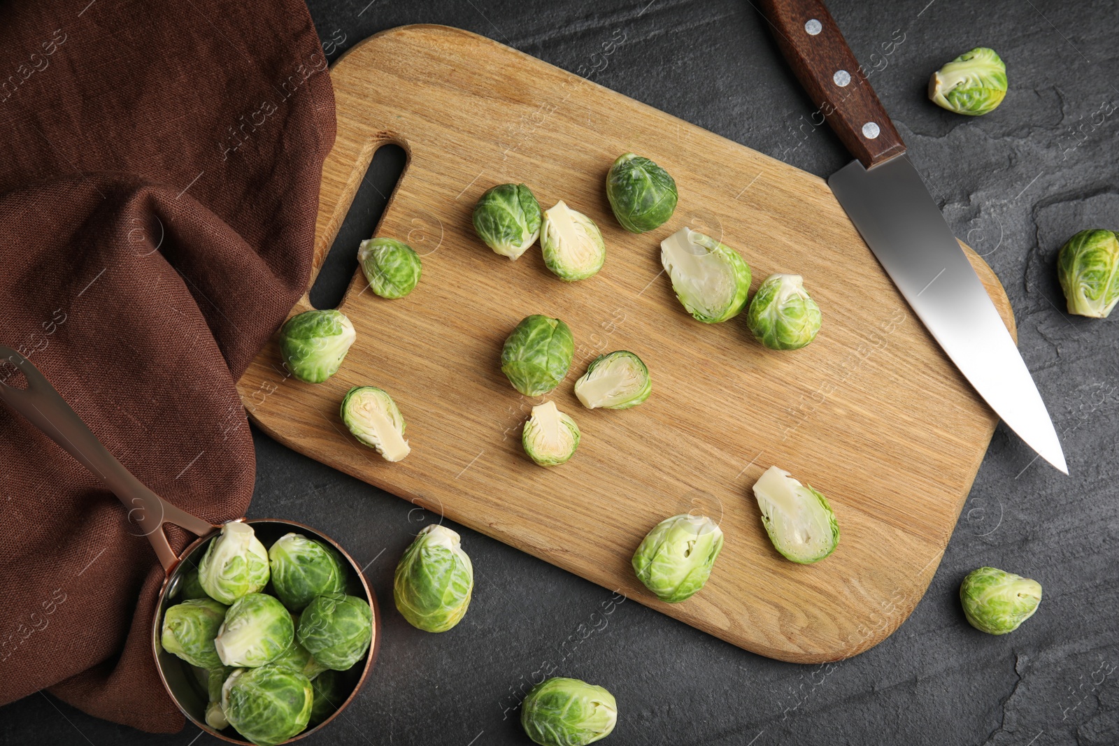 Photo of Fresh Brussels sprouts on black slate table, flat lay