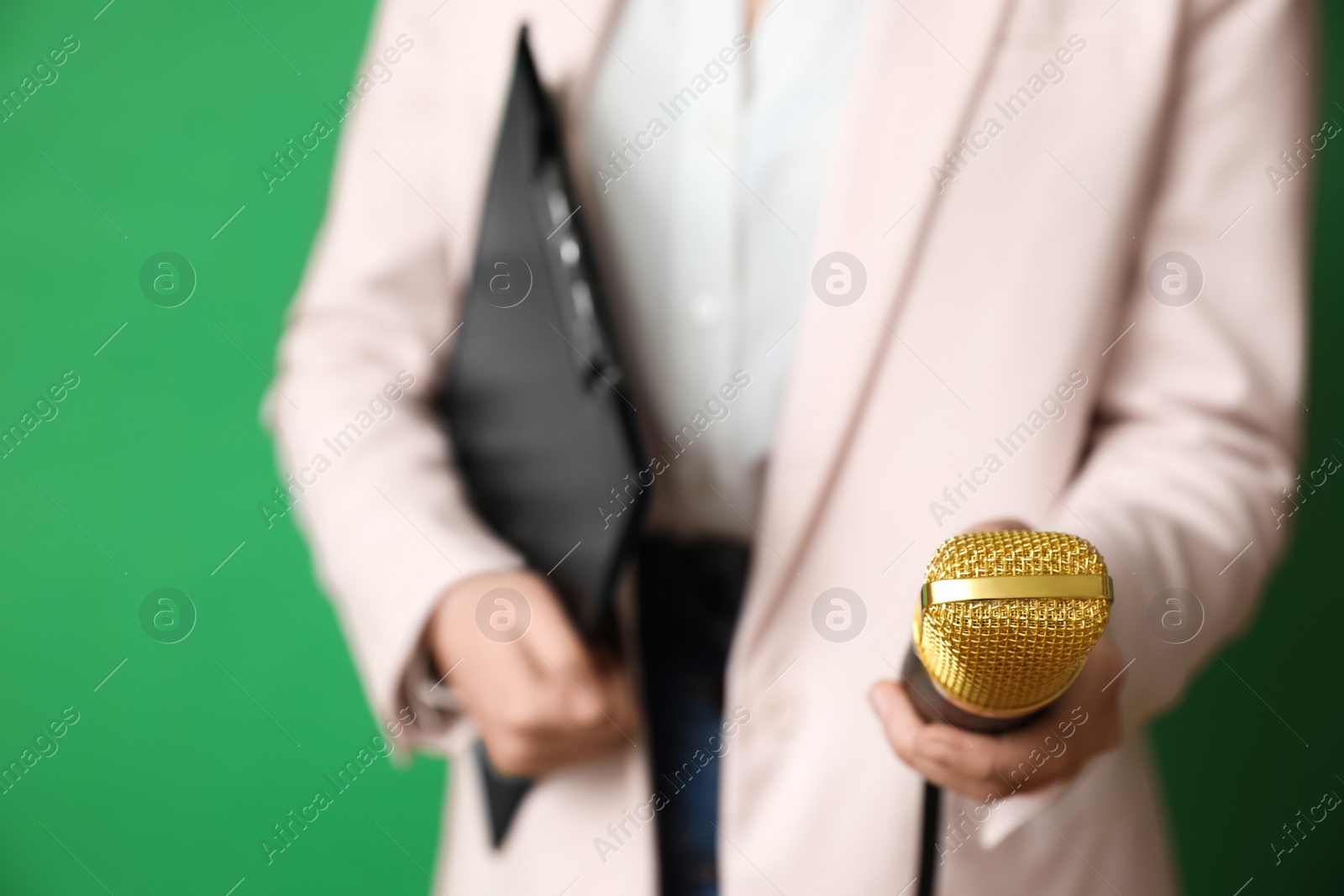 Photo of Journalist with microphone and clipboard on green background, closeup