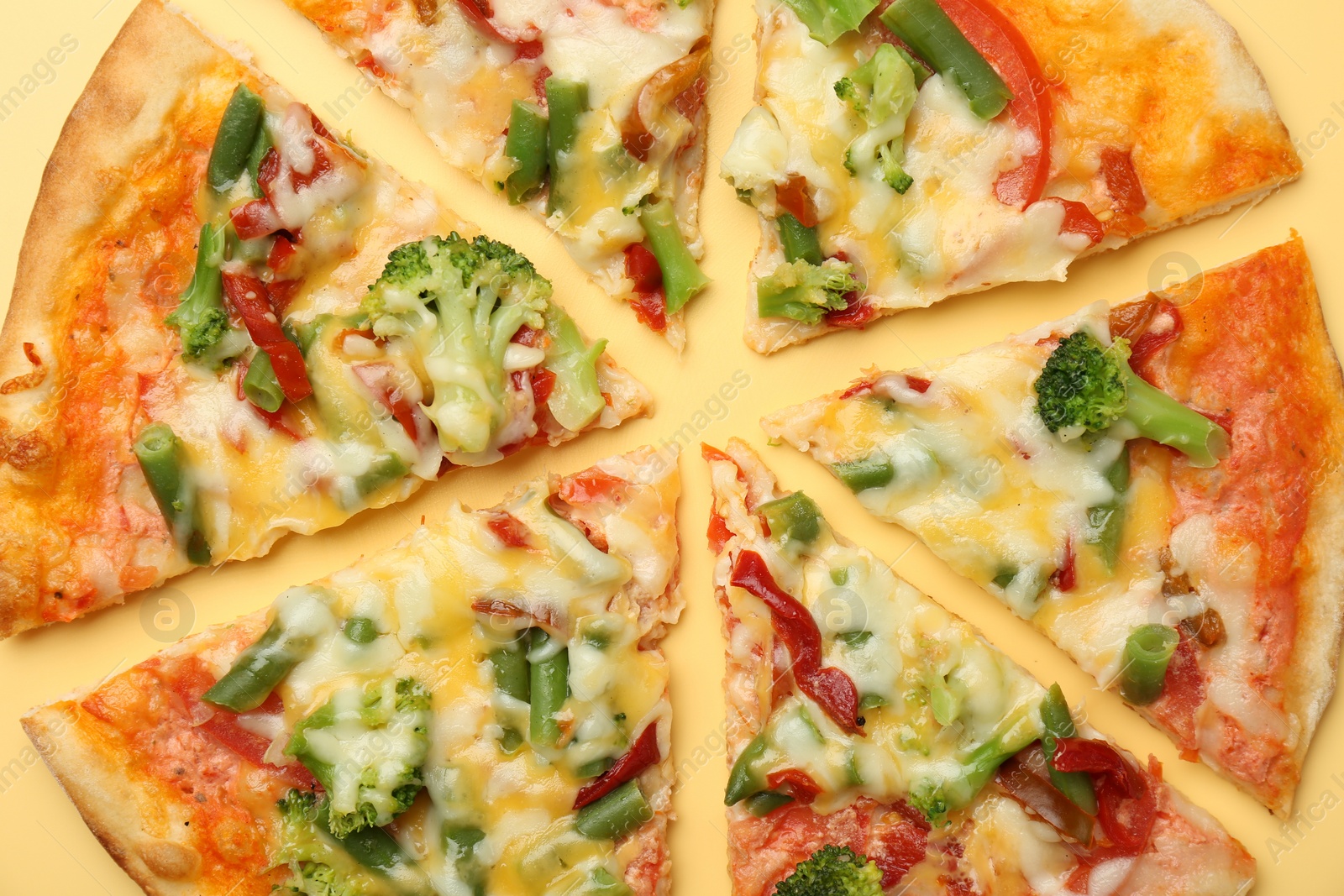 Photo of Delicious vegetarian pizza on yellow table, top view