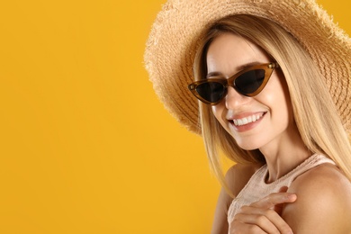 Beautiful woman in stylish sunglasses on yellow background. Space for text