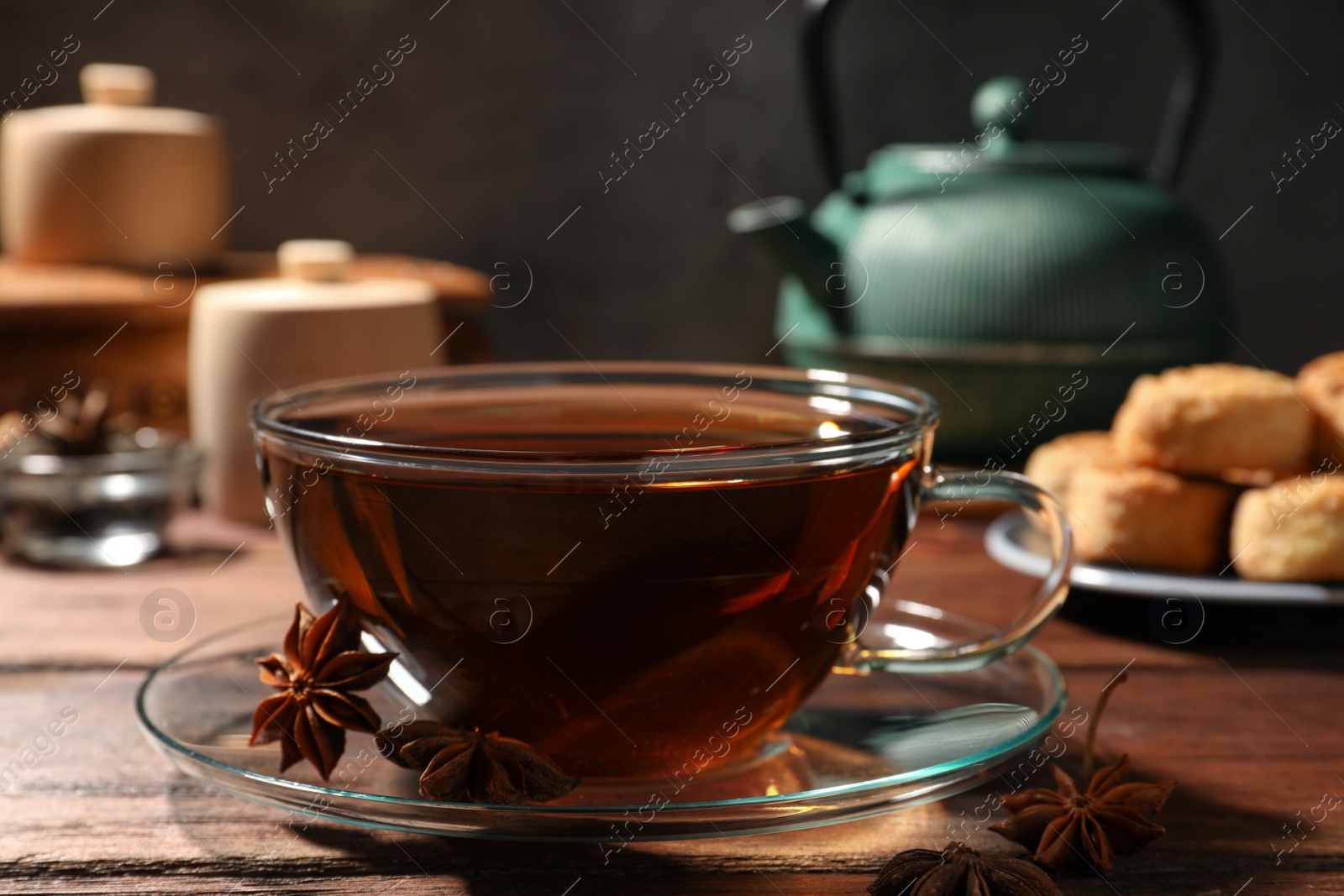 Photo of Aromatic tea with anise stars on wooden table, closeup