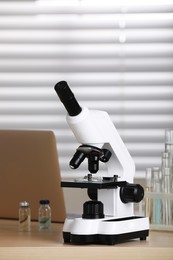 Photo of Modern medical microscope on wooden table in laboratory