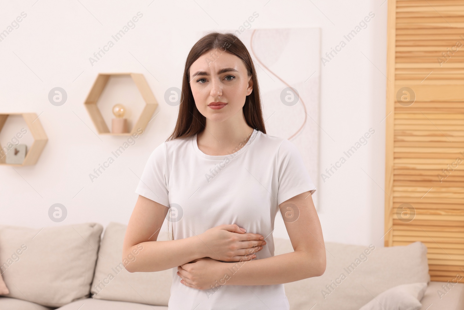 Photo of Young woman suffering from stomach pain at home