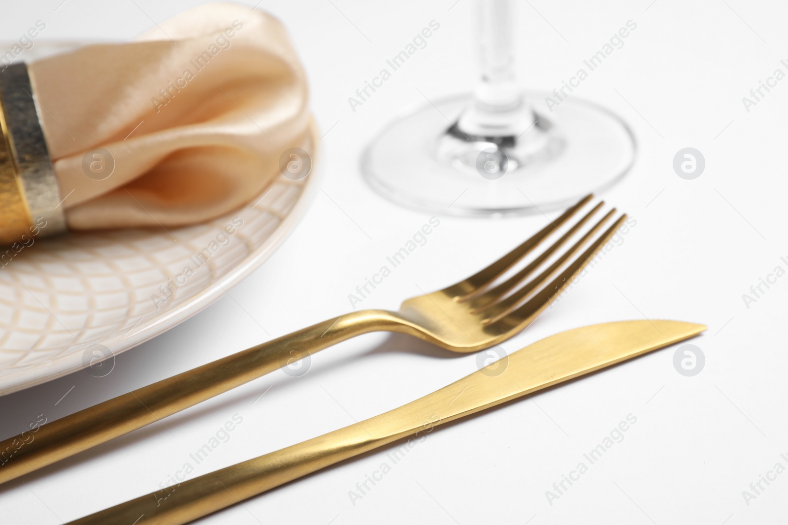 Photo of Beautiful table setting with golden cutlery and beige napkin on white background, closeup