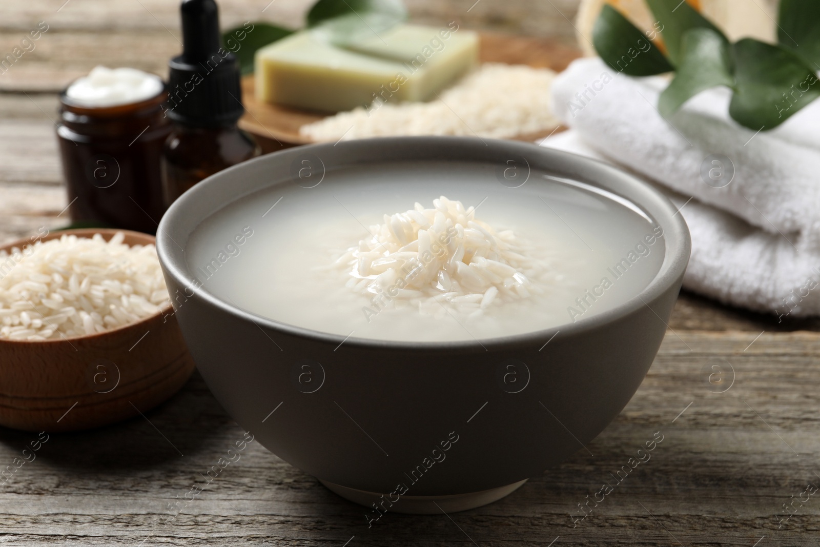 Photo of Bowl with rice soaked in water on wooden table