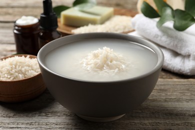 Photo of Bowl with rice soaked in water on wooden table