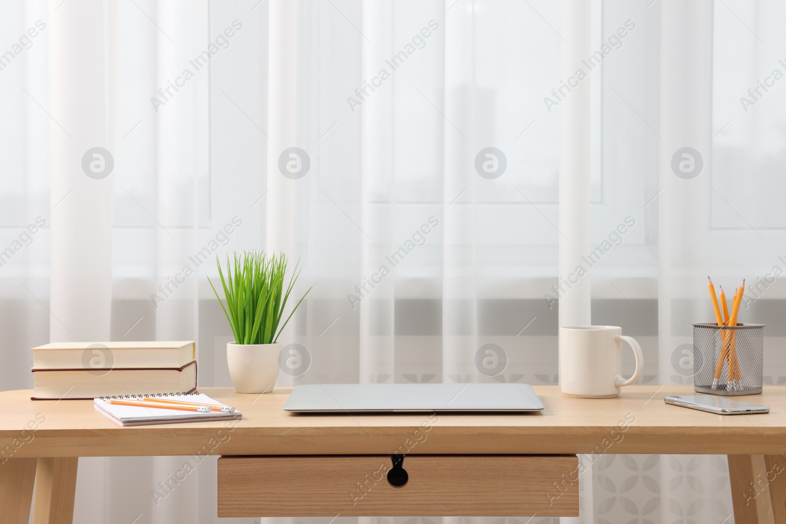 Photo of Home office. Stylish workplace with laptop and stationery on wooden desk indoors. Space for text