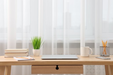 Photo of Home office. Stylish workplace with laptop and stationery on wooden desk indoors. Space for text