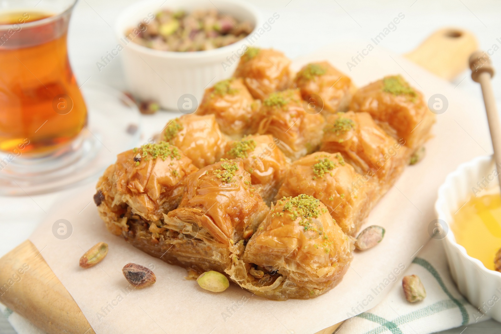 Photo of Delicious sweet baklava with pistachios on wooden board, closeup