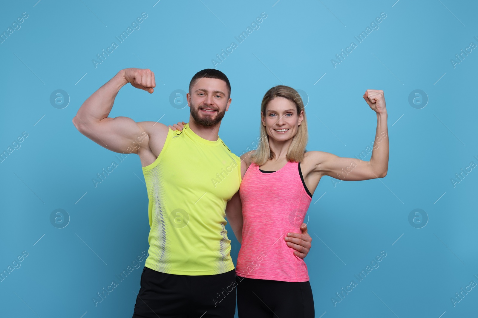 Photo of Athletic people showing muscles on light blue background