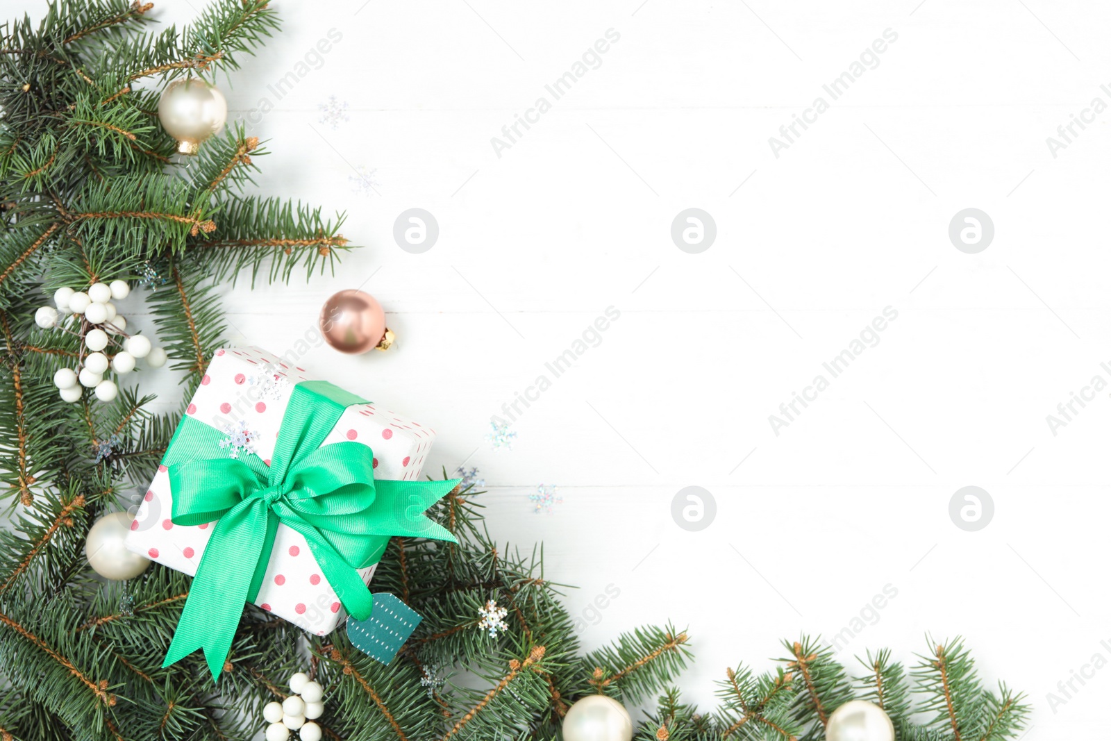 Photo of Flat lay composition with Christmas gift box and decor on white wooden table, space for text