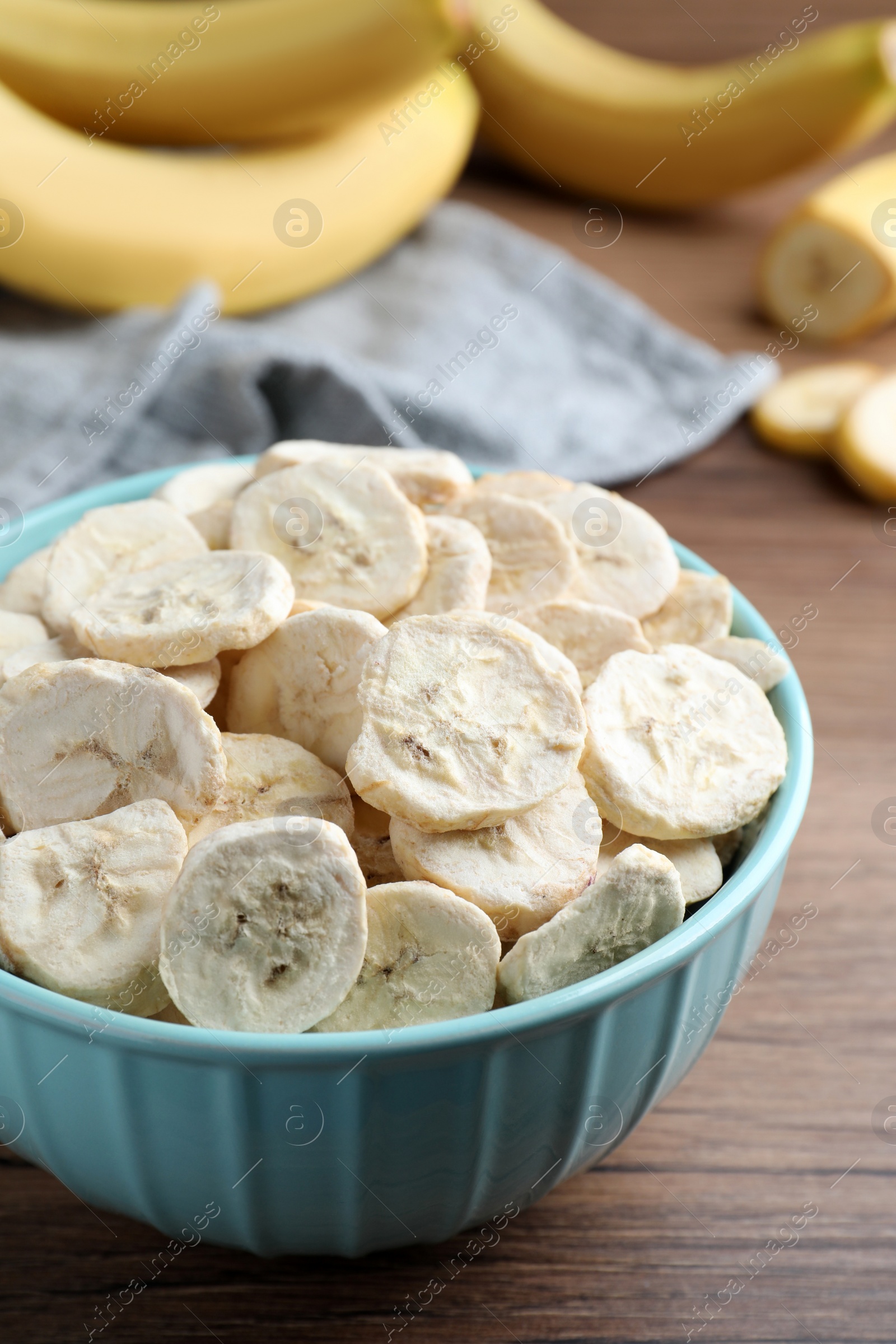 Photo of Freeze dried and fresh bananas on wooden table, closeup