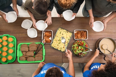 Photo of Volunteers serving food to poor people indoors, top view