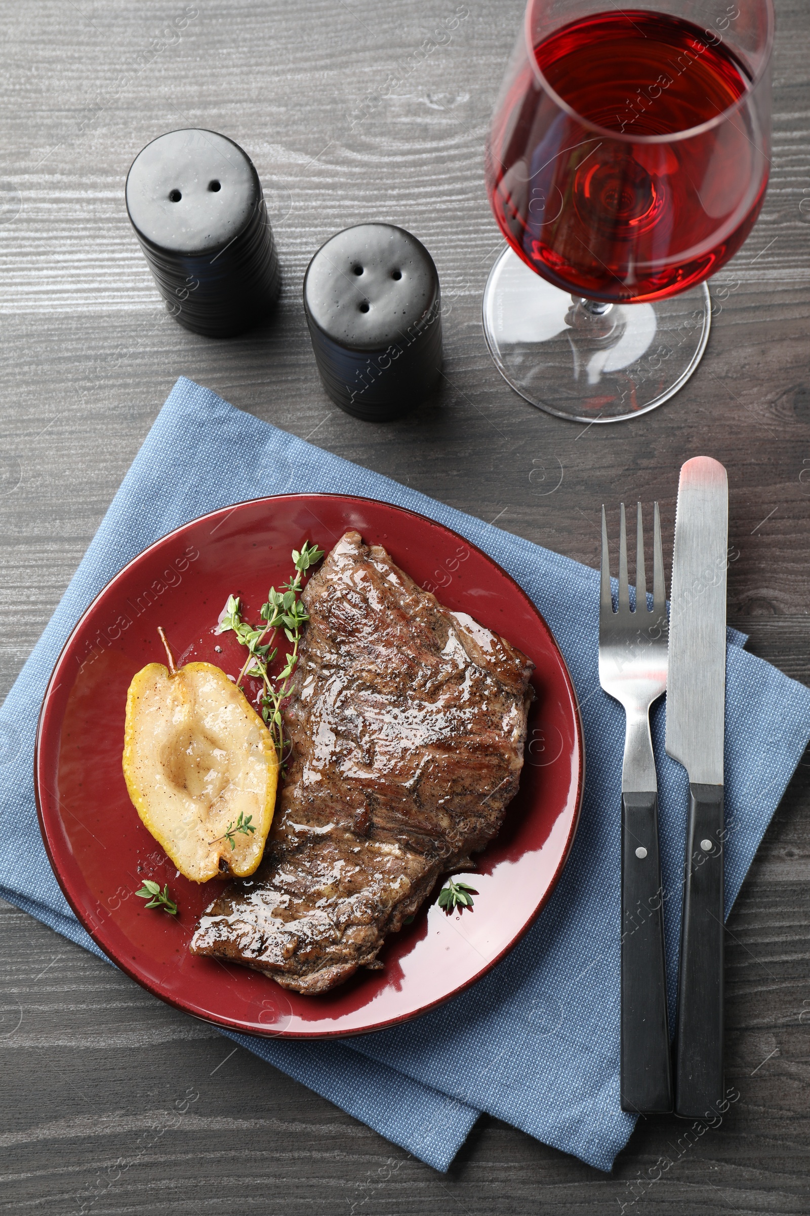 Photo of Delicious roasted beef meat and caramelized pear served on grey wooden table, flat lay