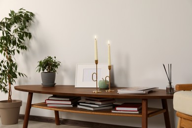 Wooden table with decorative elements near light wall in room. Interior design