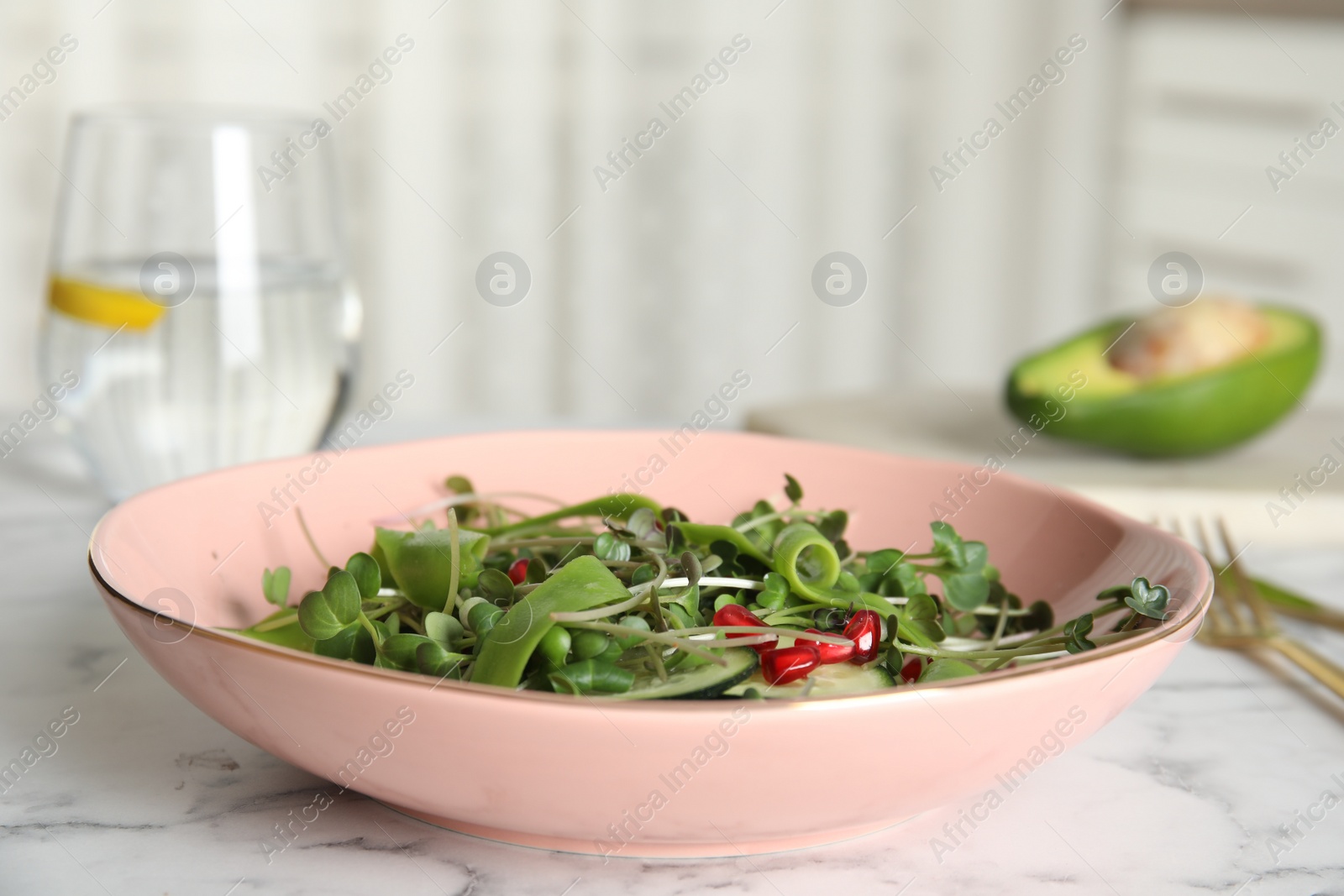 Photo of Salad with fresh organic microgreens in bowl on white marble table indoors