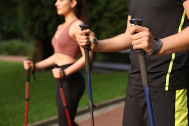 Photo of Couple practicing Nordic walking with poles outdoors, selective focus