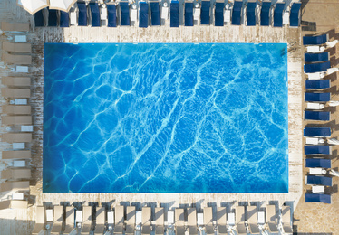 Image of Sun lounge chairs near swimming pool, top view