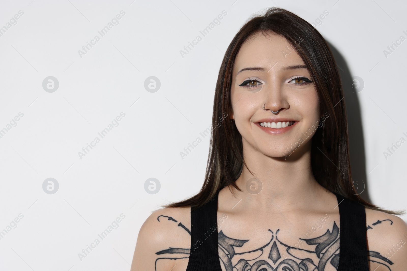 Photo of Portrait of smiling tattooed woman on light background. Space for text