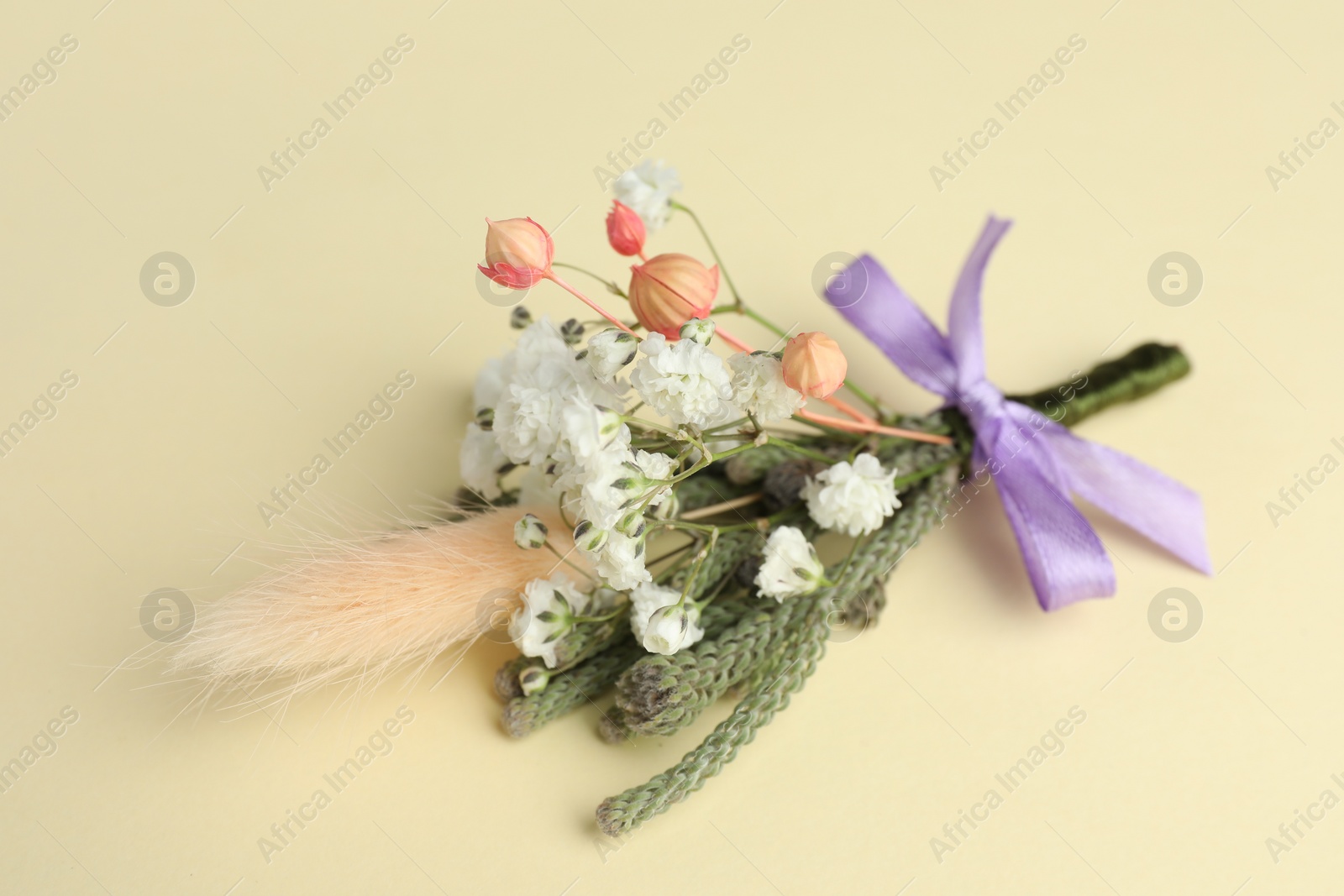 Photo of Small stylish boutonniere on beige background, closeup