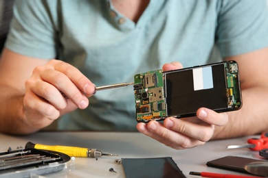 Technician repairing mobile phone at table, closeup