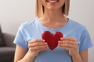 Photo of Young woman holding red heart indoors, closeup. Volunteer concept