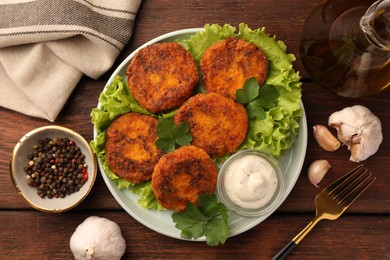 Tasty vegan cutlets with sauce and ingredients on wooden table, flat lay