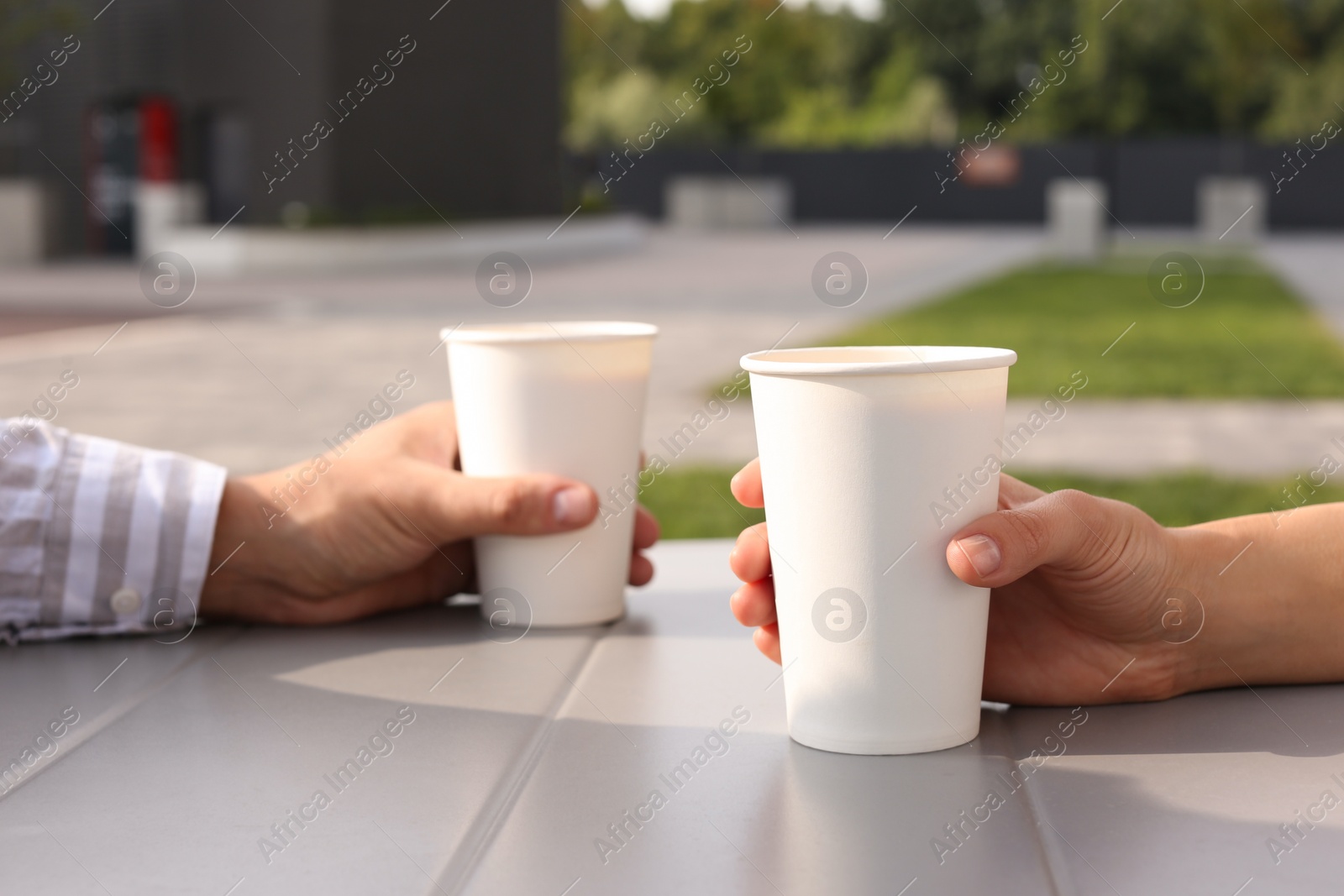 Photo of Coffee to go. Couple with paper cups at table outdoors, selective focus