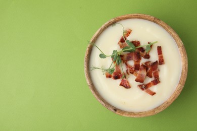 Photo of Delicious potato soup with bacon and microgreens in bowl on green table, top view. Space for text