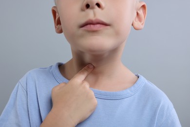 Photo of Endocrine system. Little boy doing thyroid self examination on light grey background, closeup