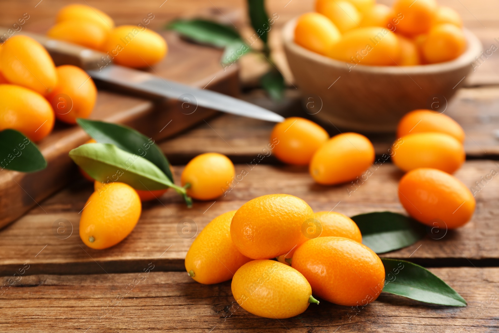 Photo of Fresh ripe kumquats and leaves on wooden table