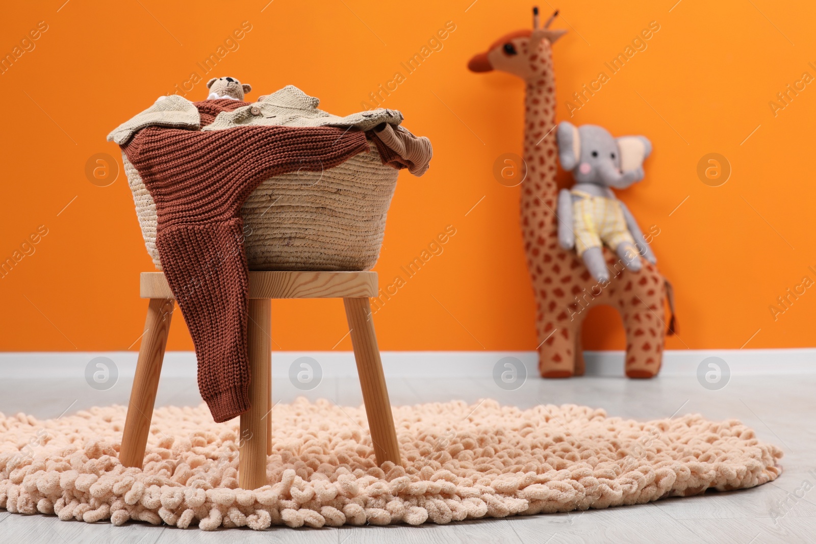 Photo of Laundry basket with baby clothes and toys in child room