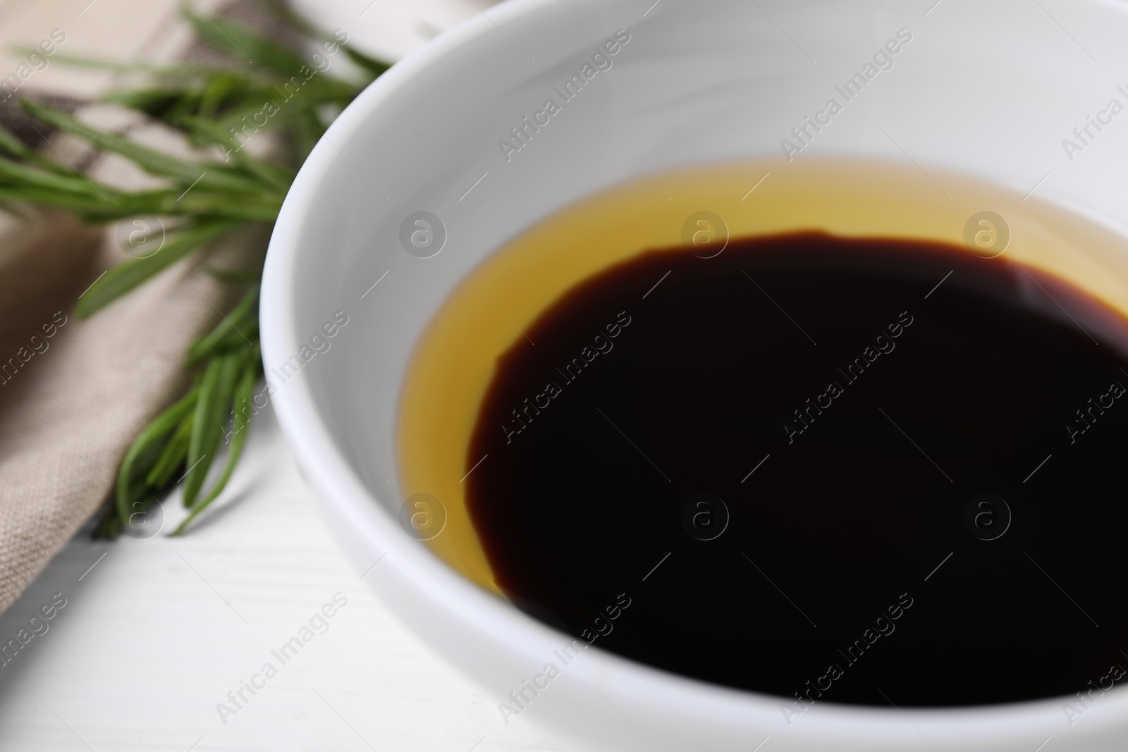 Photo of Bowl of balsamic vinegar with oil on white table, closeup