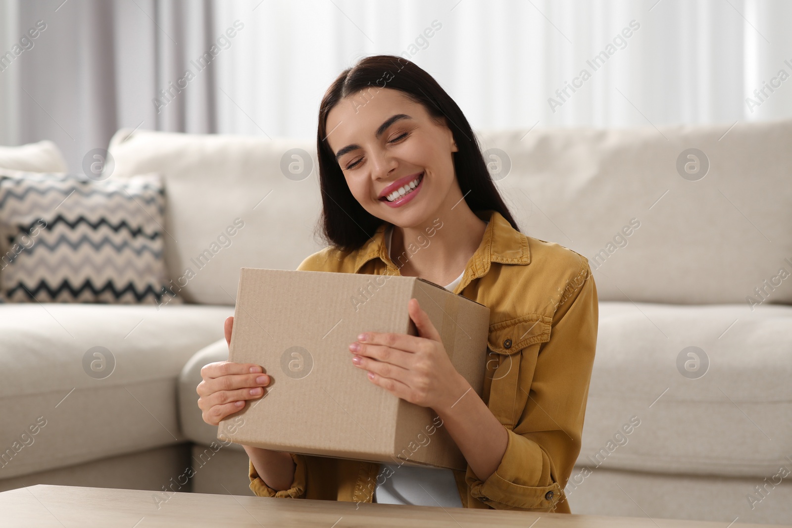 Photo of Happy young woman with parcel at home. Internet shopping