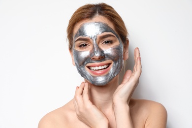 Beautiful woman with mask on face against light background