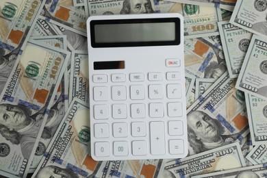 Photo of Money exchange. Dollar banknotes and calculator, top view