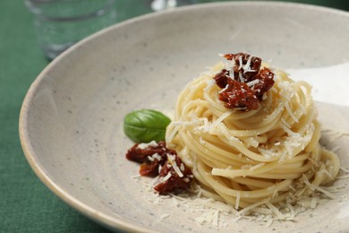 Photo of Tasty spaghetti with sun-dried tomatoes and parmesan cheese on plate, closeup. Exquisite presentation of pasta dish