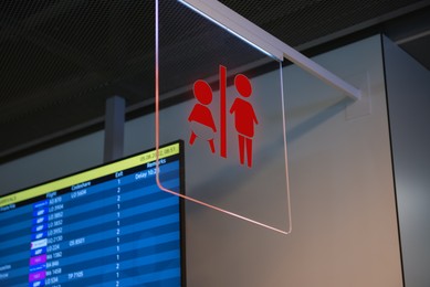 Image of Red public toilet sign on transparent glass hanging indoors