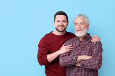 Photo of Happy son and his dad on light blue background, space for text
