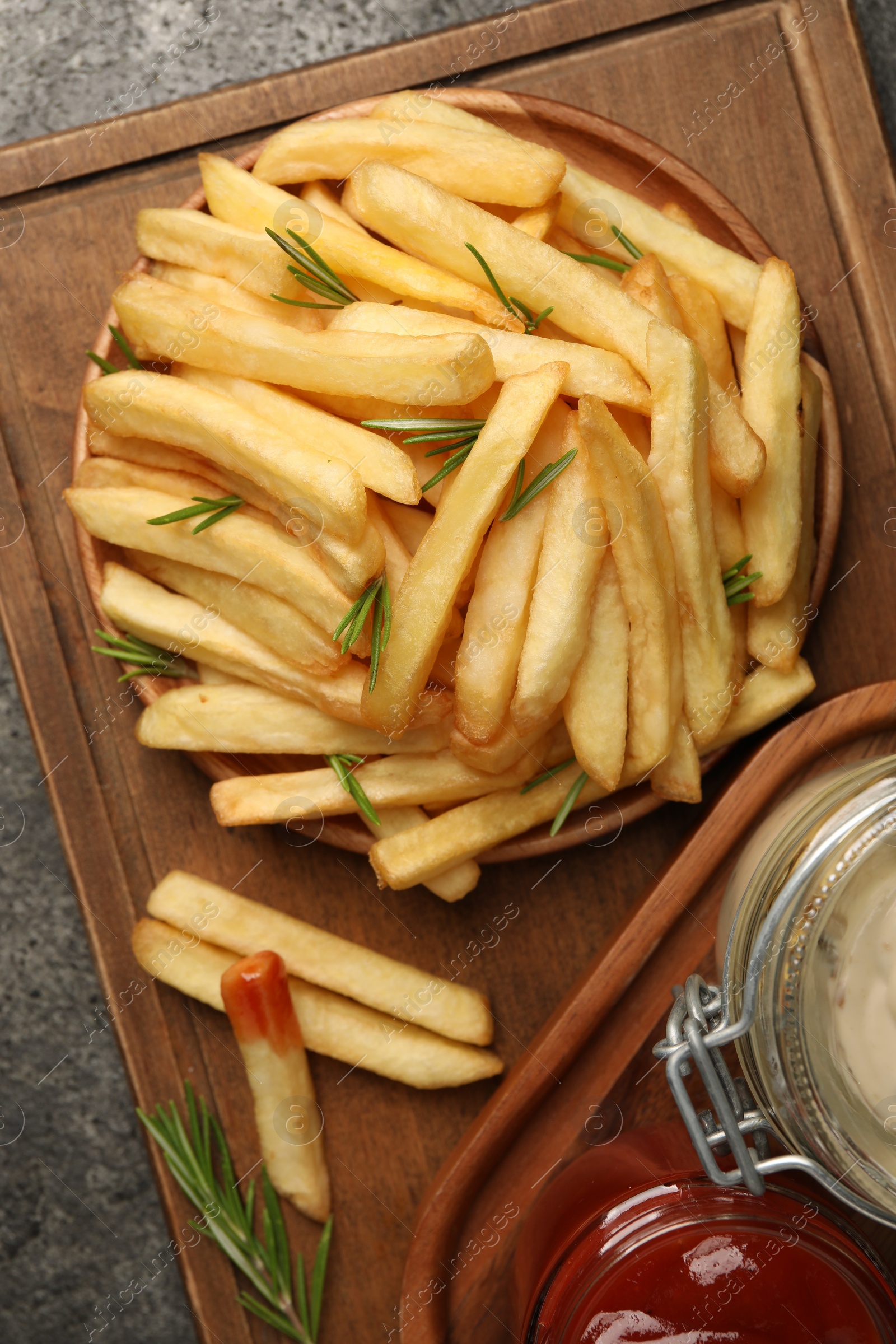 Photo of Delicious french fries served with sauces on grey textured table, top view
