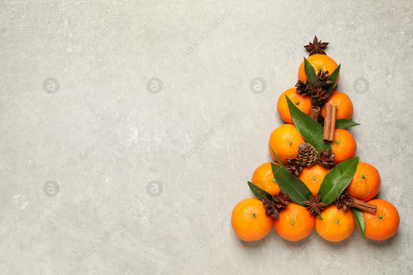 Photo of Christmas tree shape made of tangerines on light background, flat lay. Space for text