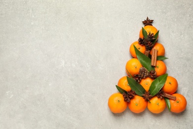 Photo of Christmas tree shape made of tangerines on light background, flat lay. Space for text