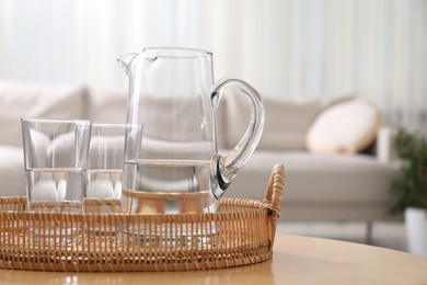 Photo of Jug and glasses with clear water on table indoors, closeup. Space for text