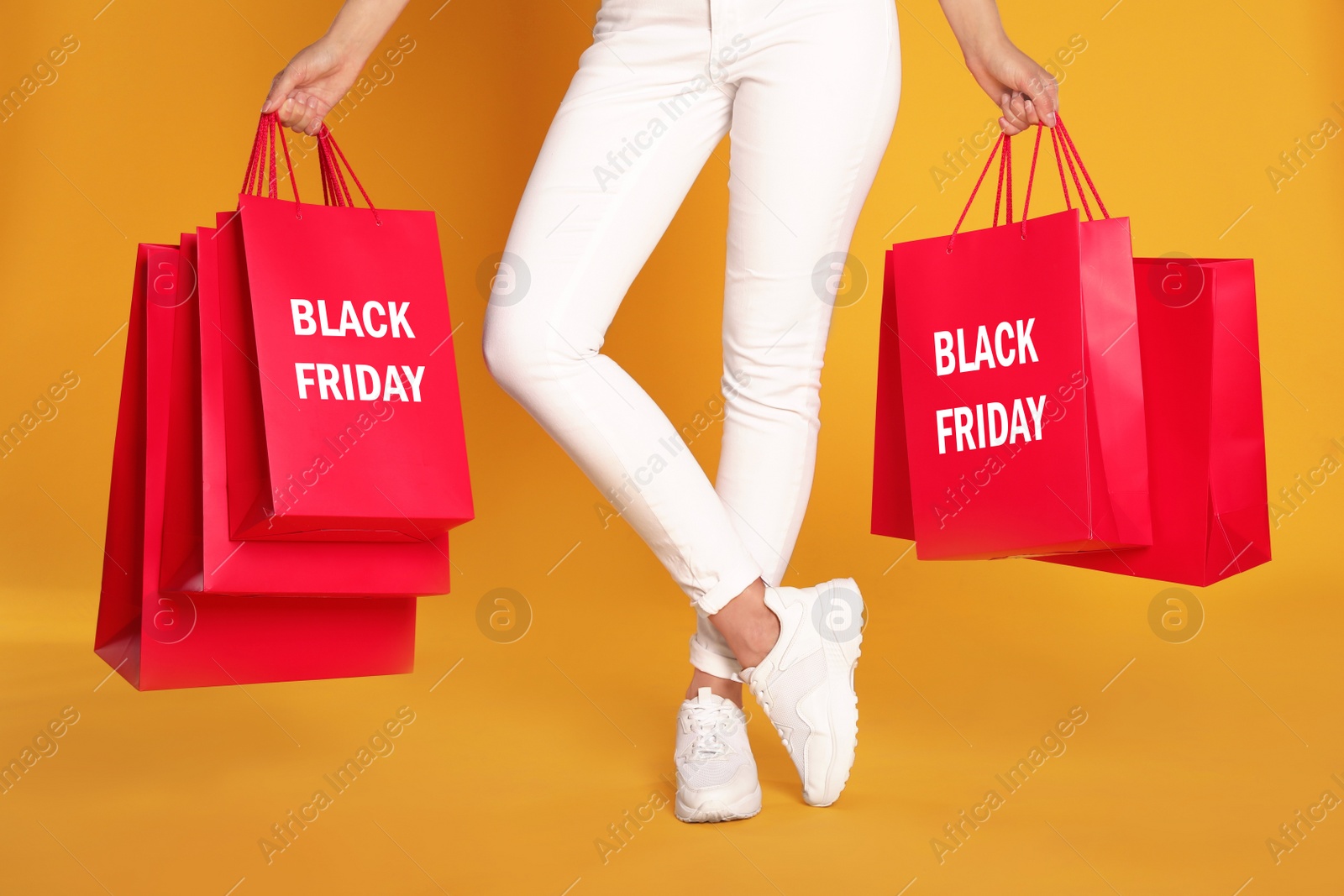 Photo of Woman with shopping bags on yellow background, closeup. Black Friday