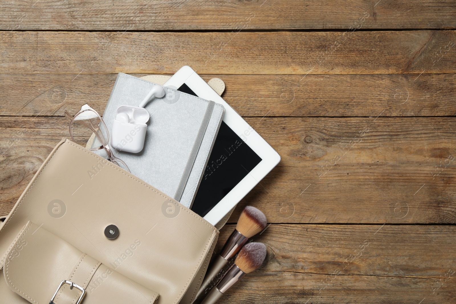 Photo of Stylish urban backpack with different items on wooden table, flat lay. Space for text