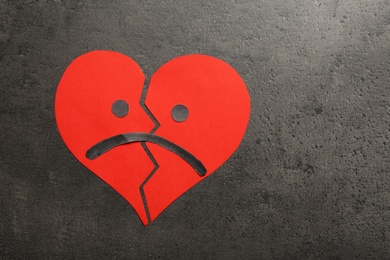 Photo of Broken heart with sad face on grey background, flat lay. Space for text